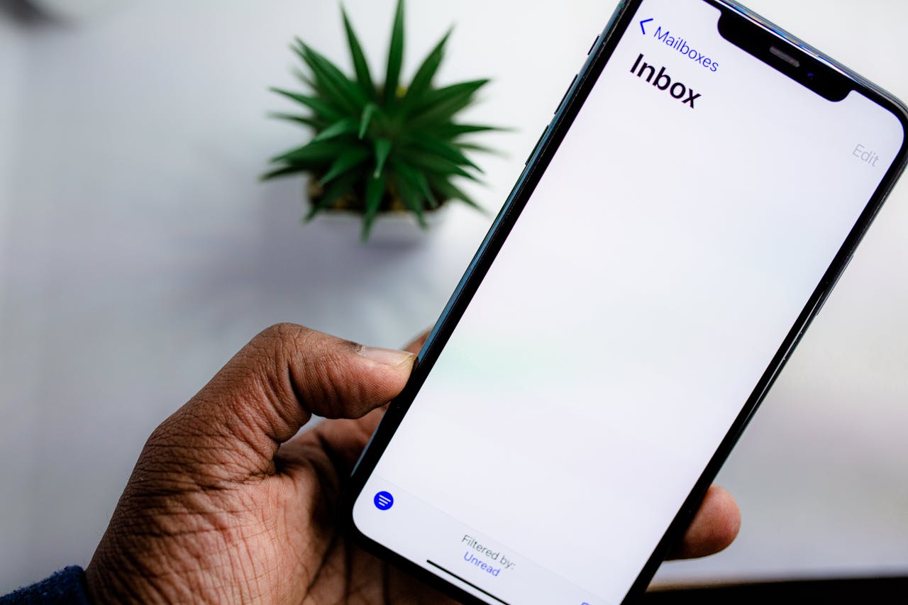 heros-img A close-up view of a smartphone screen displaying the email inbox, held by an adults hand.